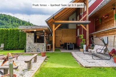 a patio of a house with a bench and grass at Apartmaji pri Jožu in Bohinj