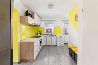 a kitchen with white cabinets and yellow walls at Apartmaji pri Jožu in Bohinj