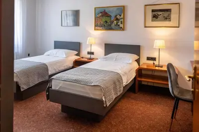 a hotel room with two beds and a desk with two lamps at Hotel Sporn in Radomlje