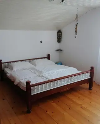 a bed sitting on a wooden floor in a room at at Marian's place in Spuhlja
