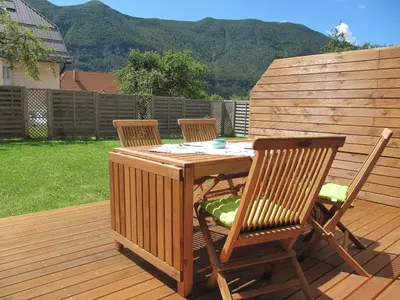 a wooden table and two chairs on a deck at Apartments Supermjau in Bovec