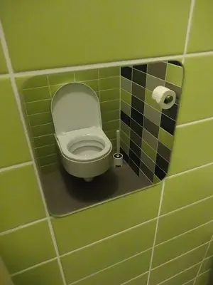 a bathroom with a toilet in a green tiled wall at Apartments Supermjau in Bovec