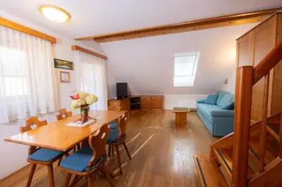 a living room with a table and a blue couch at Apartma in Bungalov Jezerci in Gozd Martuljek