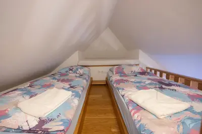 two beds in a small room with white curtains at Apartma in Bungalov Jezerci in Gozd Martuljek