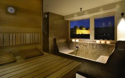 a room with a tub and a window with a clock at Hotel Maribor & Garden Rooms in Maribor