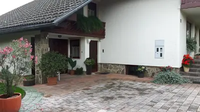 a white house with potted plants on a patio at Apartments Magdalena in Radovljica