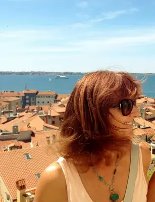 a woman wearing sunglasses looking out over a city at Apartments Magdalena in Radovljica