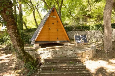a small wooden house sitting on top of a stone wall at Kraška hiša Škrla in Divača