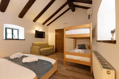 a bedroom with two bunk beds and a chair at Kraška hiša Škrla in Divača