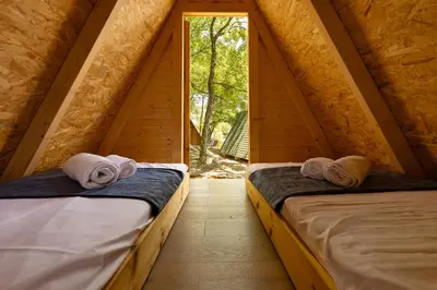 two beds in a small room with a window at Kraška hiša Škrla in Divača