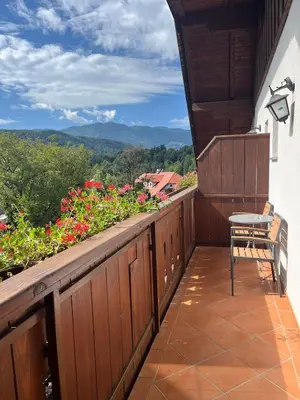 a wooden balcony with a chair and flowers at Šport center Prodnik in Ljubno