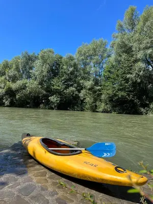 a yellow kayak sitting on the side of a river at Šport center Prodnik in Ljubno