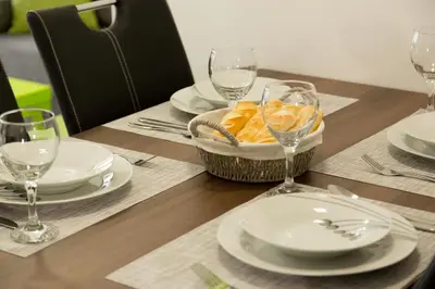 a wooden table with plates and wine glasses on it at Apartma Mariposa Banovci in Banovci