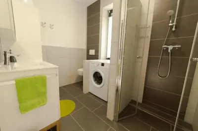 a bathroom with a shower and a washing machine at Apartma Mariposa Banovci in Banovci