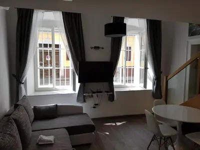 a living room with a couch and a table and two windows at SIPPO Apartments in Ljubljana