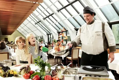 a chef standing in front of a table with food at Špik Alpine Resort in Kranjska Gora
