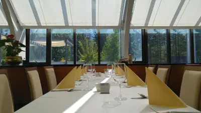 a long table with wine glasses in a room with windows at Špik Alpine Resort in Kranjska Gora
