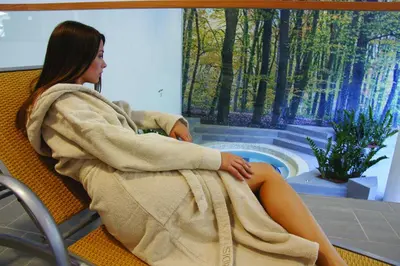 a woman in a towel sitting in a chair with a pool at Špik Alpine Resort in Kranjska Gora