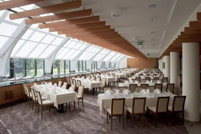 a dining room with white tables and chairs and windows at Špik Alpine Resort in Kranjska Gora