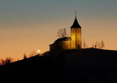 a building on top of a hill at sunset at Apartma Metka Leše Tržič in Leše