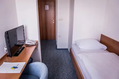 a room with a bed and a desk with a television at Hotel Bellevue in Kranj
