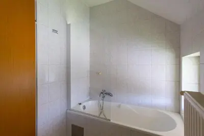 a white bath tub in a white tiled bathroom at Vacation Home Sofia in Zgornje Gorje