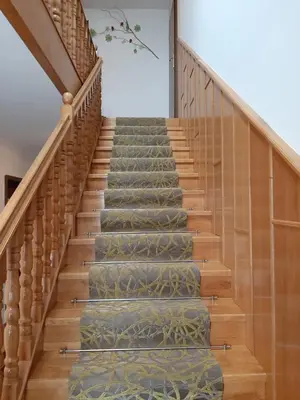 a staircase with green carpeted stairs with wooden railings at Apartmaji Tisa in Moravske Toplice