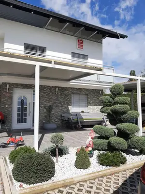 a garden with trees and bushes in front of a house at Apartmaji Tisa in Moravske Toplice