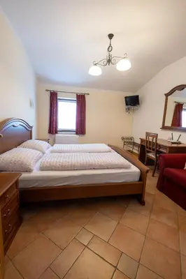 a bedroom with a large bed and a red chair at Farm Stay Malovščevo in Vitovlje