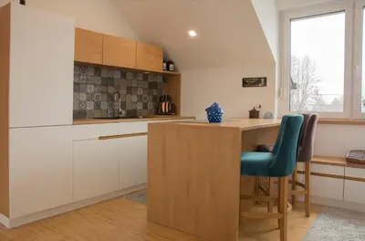 a kitchen with white cabinets and a counter with a green chair at Vintage Design Apartment in Gornja Radgona