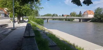 a river with benches and a bridge in the background at Vintage Design Apartment in Gornja Radgona
