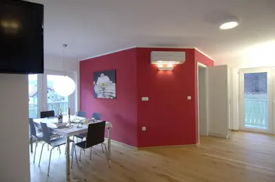 a dining room with a table and a red wall at Apartments & Wellness Skok in Mozirje