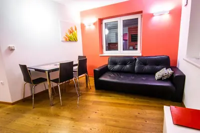 a living room with a black leather couch and a table at Apartments & Wellness Skok in Mozirje