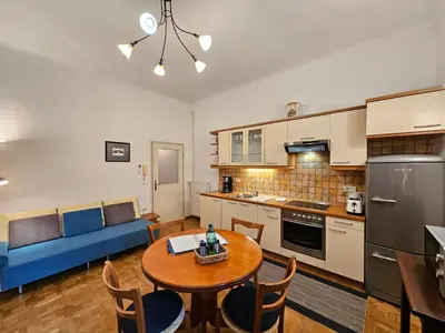 a kitchen and living room with a table and a blue couch at Spacious central studio Nika 2 Tour As Ljubljana in Ljubljana
