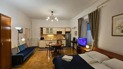 a room with a bed and a living room with a kitchen at Spacious central studio Nika 2 Tour As Ljubljana in Ljubljana