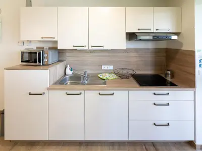 a kitchen with white cabinets and a sink at Apartmaji BANONIA 