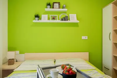 a green bedroom with a bed with a bowl of fruit on it at Apartmaji BANONIA 