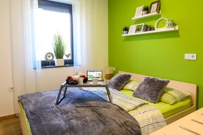 a green bedroom with a bed with a table on it at Apartmaji BANONIA 