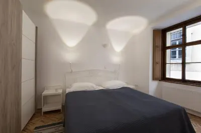 a white bedroom with a bed and a window at River and Castle View Apartment Rose Tour As Ljubljana in Ljubljana