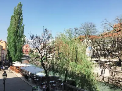 a city street with tables and chairs and trees at River and Castle View Apartment Rose Tour As Ljubljana in Ljubljana