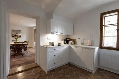 a kitchen with white cabinets and a dining room at River and Castle View Apartment Rose Tour As Ljubljana in Ljubljana