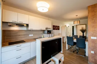 a kitchen with white cabinets and a tv in a room at Apartmaji BANONIA 