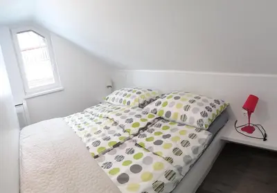 a white bed with polka dot sheets and a window at APARTMENTS 1A RIBNO - BLED in Bled