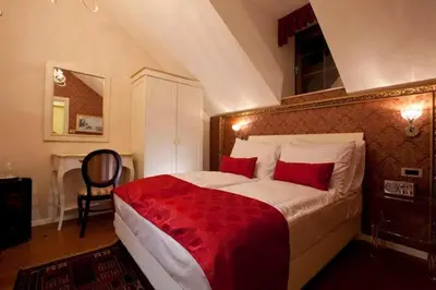 a bedroom with a large bed with red pillows at Hotel Actum in Kranj