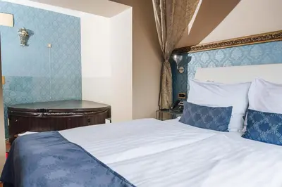 a bedroom with a large bed with blue walls at Hotel Actum in Kranj
