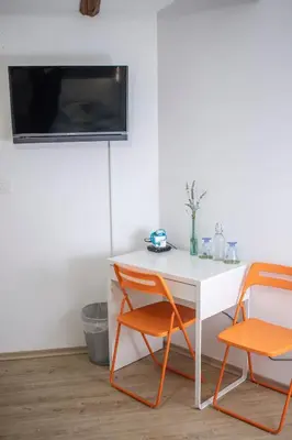 a desk with two chairs and a tv on a wall at Borea Rooms - Sobe Budanje in Vipava