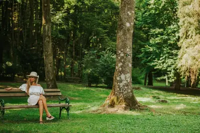 a woman sitting on a bench in a park at Hotel Vitarium Superior - Terme Krka in Smarjeske Toplice