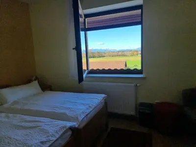 a bedroom with a bed and a window with a field at Bed and Breakfast Valjavec in Kranj