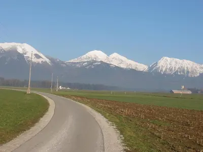 a dirt road with snow covered mountains in the background at Bed and Breakfast Valjavec in Kranj