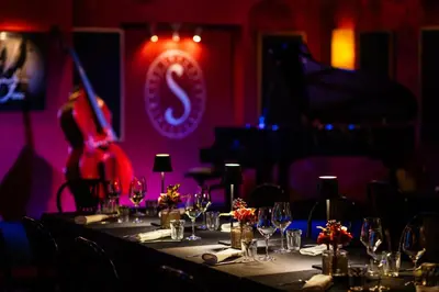 a table with wine glasses in a room with a guitar at Hotel Slamič Ljubljana in Ljubljana